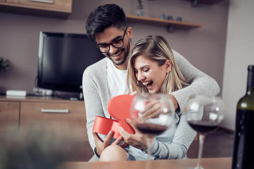 Namorado surpreendendo namorada com presente romântico em caixa de coração